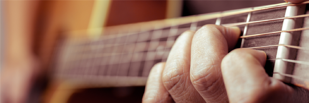 Nahaufnahme einer Hand die eine Gitarre hält.